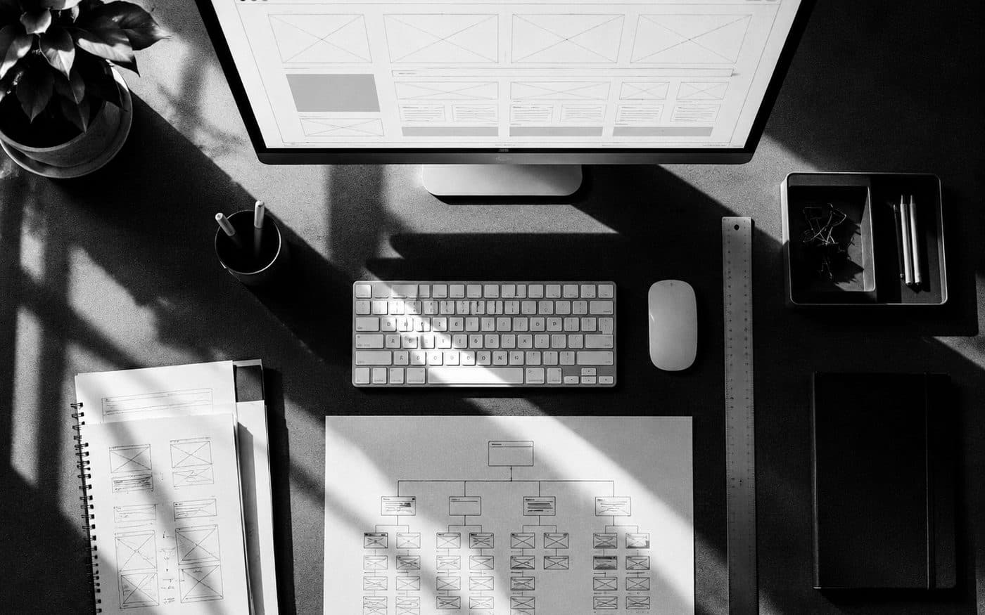 Escritorio con el esquema de una web en pantalla y el mapa del sitio dibujado en papel